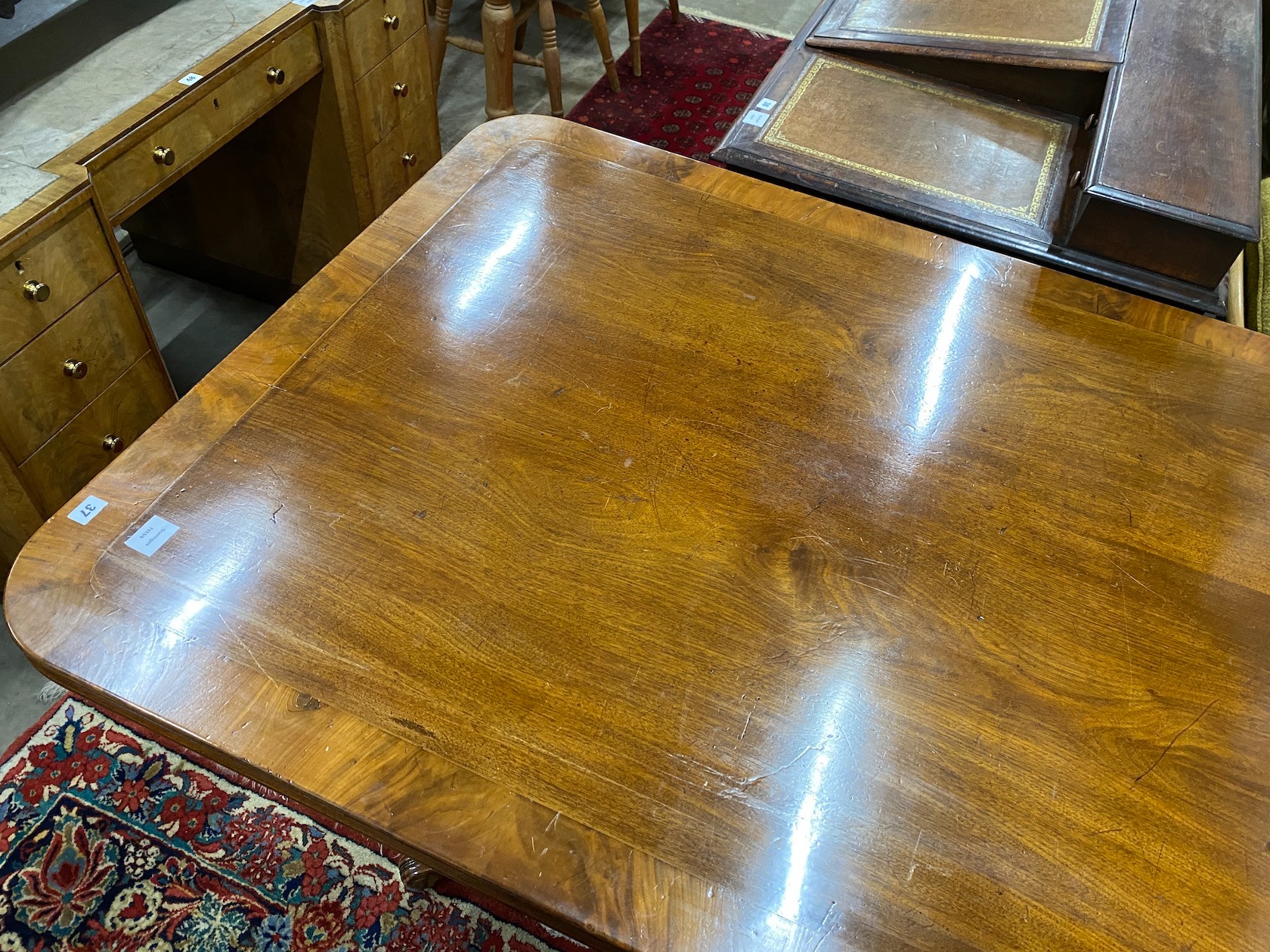 A Regency banded mahogany rectangular tilt top dining table, length 141cm, depth 106cm, height 75cm